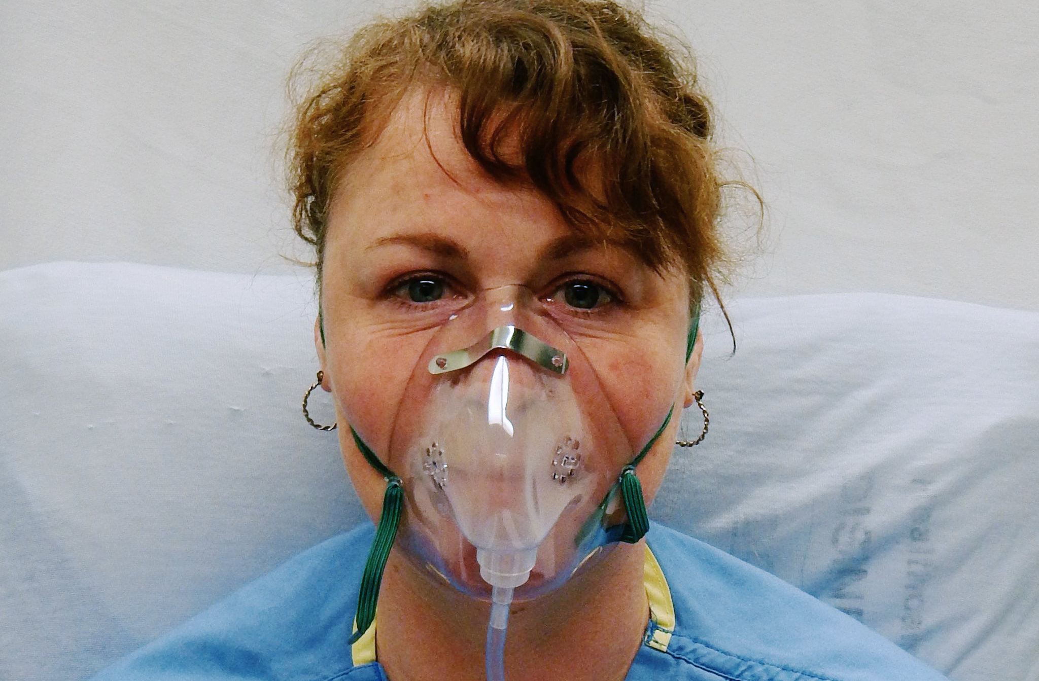Sjuksköterska som demonstrerar hur man ska sätta på sig en syrgasmask.